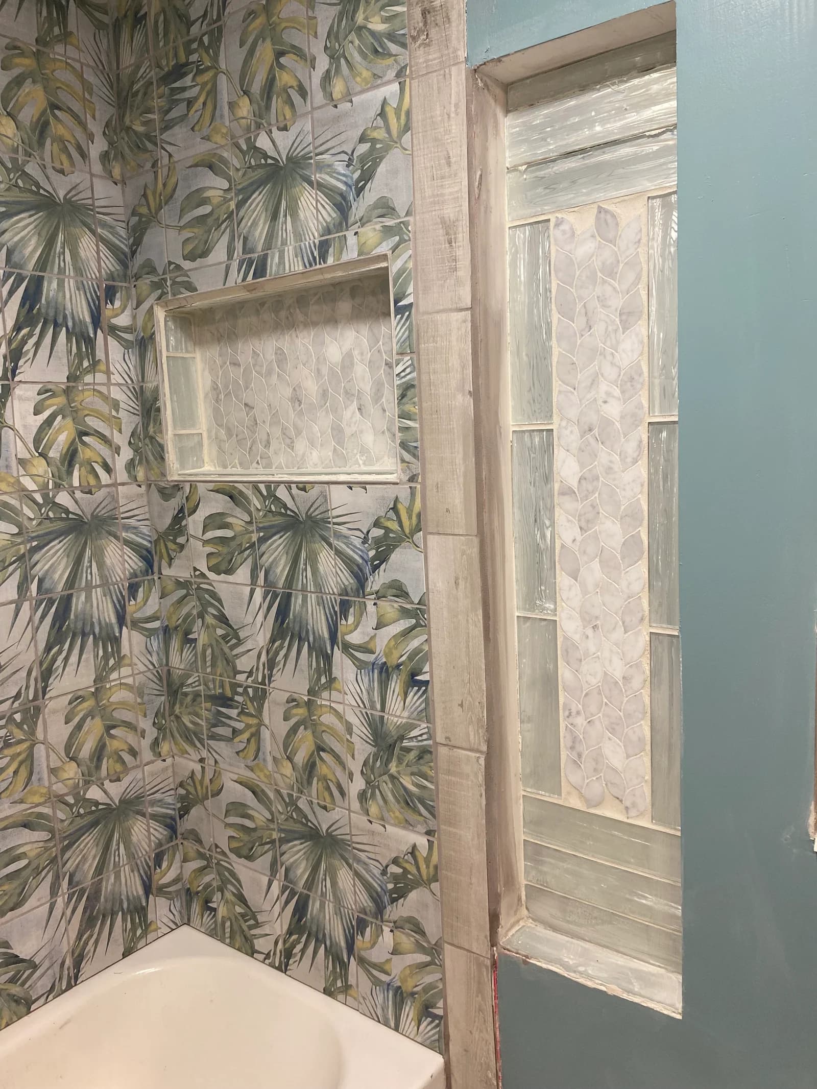 Botanical wall pattern beside a tiled shower niche and glass-block window