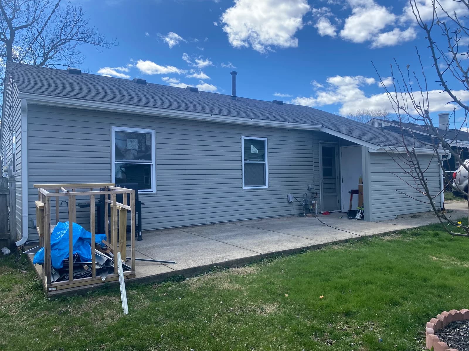 Rear exterior with gray siding, a covered doorway, and a paved patio