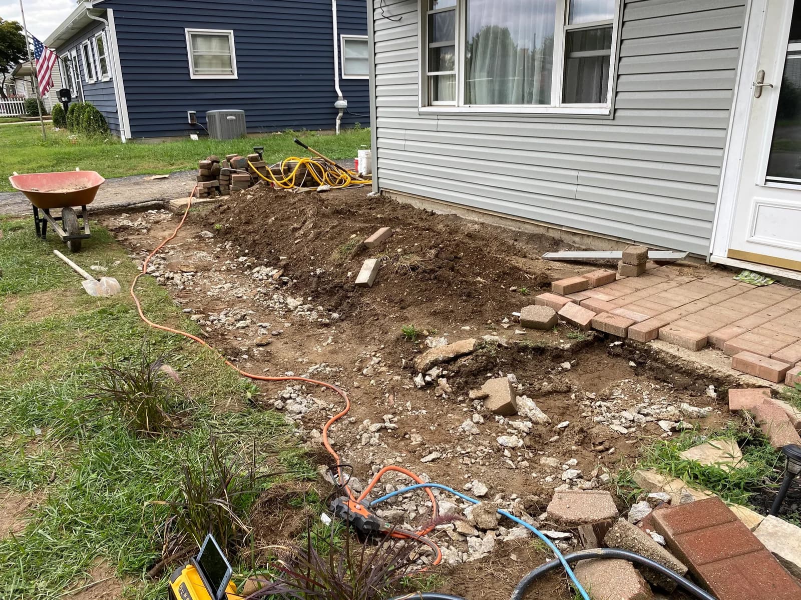 Patio area with excavated ground, pavers, and tools during the work